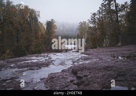 Moody view of the bridge and forest in Gooseberry Falls State Park on a foggy autumn day in Minnesota Stock Photo