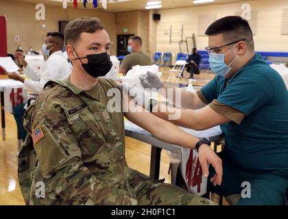 U.S. Army Spc. Klayton McCallum, a combat medic with Headquarters and Headquarters Company, 2nd Battalion, 108th Infantry Regiment, 27th Infantry Brigade Combat Team, 42nd Infantry Division, New York National Guard, receives his first dose of the COVID-19 vaccine at Naval Support Activity Bethesda, Md., Feb. 19, 2021. McCallum is one of more than 500 citizen-Soldiers from New York currently supporting civil authorities in Washington, D.C. The National Guard has been requested to continue supporting federal law enforcement agencies with security, communications, medical evacuation, logistics an Stock Photo