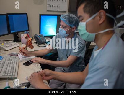 210219-N-LW757-1010  SAN DIEGO (Feb. 19, 2021) Hospital Corpsman 3rd Class Adan Garcia, a cardiovascular technologist (left), and Hospital Corpsman 1st Class Andres Aquino, a cardiovascular technologist student (right), both assigned to Naval Medical Center San Diego (NMCSD), discuss how to steer an electrophysiology ablation catheter in the hospital's cardiac catheterization laboratory Feb. 19. Cardiovascular technologists prepare patients for procedures, connect patients to any necessary diagnostics and monitoring equipment, operate diagnostics systems and carry out any non-medical procedure Stock Photo