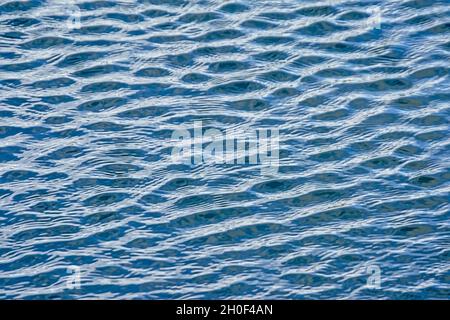 Deep blue wavy water surface with silver sunlight reflections in the lake Stock Photo