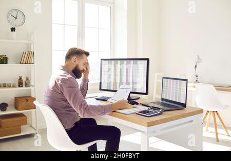 Financial accountant reading a document while doing paperwork at his office desk Stock Photo