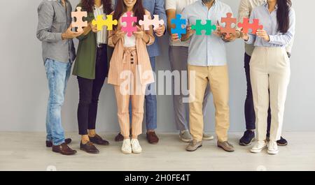 Team of creative business people standing together and joining pieces of jigsaw puzzle Stock Photo