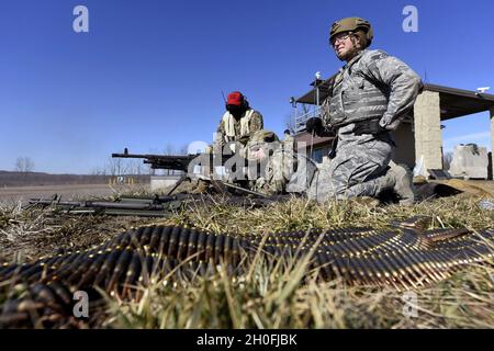 U.S. Air Force Airman 1st Class Michael Lawhead, center, an 88th Security Forces Squadron alarm monitor, fires an M240 machine gun with Senior Airman Aurielle Marvin, an 88th SFS patrolman, under the direction of Senior Airman Jerome Fogg, an 88th SFS combat arms instructor, left, at Camp Atterbury in Edinburgh, Indiana, on Feb. 25, 2021. The combat arms instructors, from Wright-Patterson Air Force Base, Ohio, travel to Camp Atterbury multiple times each year for readiness and qualification training with deployers on machine guns and grenade launchers. Stock Photo