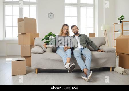 Happy young husband and wife sitting on sofa in their newly bought house or apartment Stock Photo