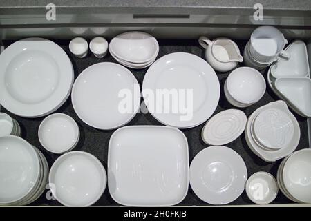 Minimalistic white crockery organised in large storage drawers in a domestic kitchen Stock Photo