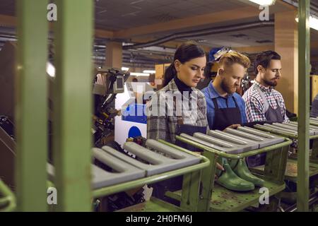 Group of young workers working in manufacturing workshop at footwear making factory Stock Photo