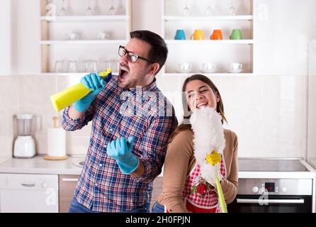 Happy young couple doing chores, singing and having fun Stock Photo