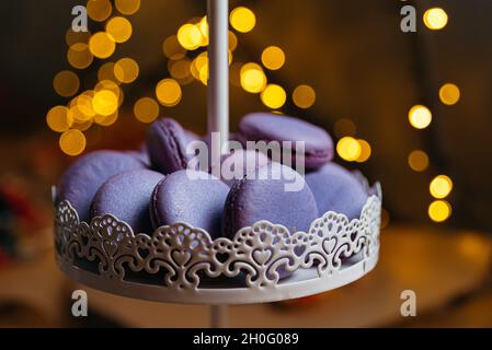 Lilac macaroons on a dessert stand. In the background, a bokeh effect from the yellow lights. Stock Photo