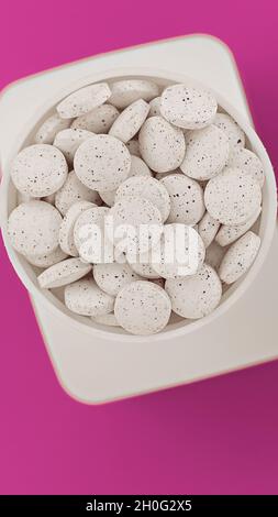 white pills on pink background close-up. white dietary supplements vertical Stock Photo