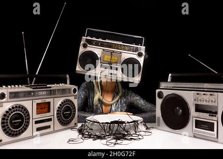 Woman with ghettoblaster as a head eating cassette tape Stock Photo