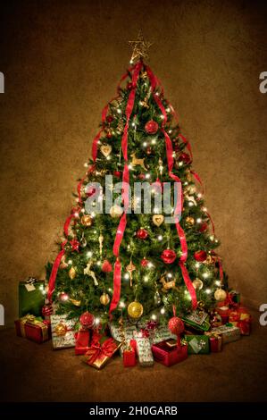 Lovely Christmas Tree decorated in traditional red and gold with red ribbon coming down. Processed to give a slightly surreal and glowing effect Stock Photo