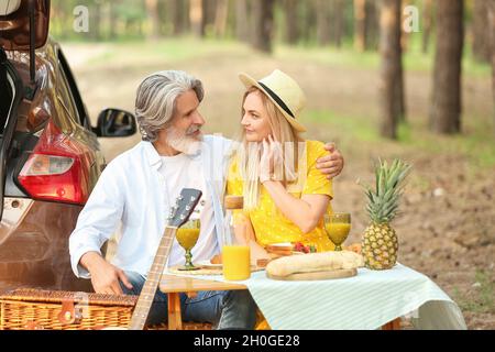Happy mature couple having picnic in forest Stock Photo