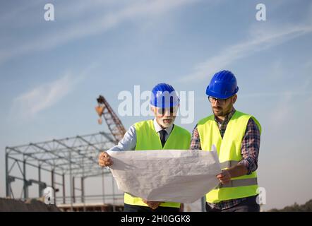 Two engineers talking at building site with metal construction in background Stock Photo