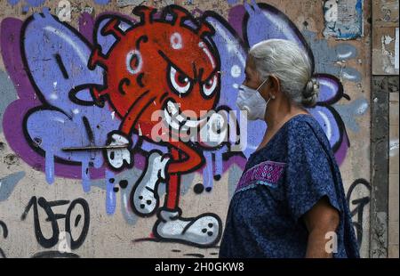 Mumbai, Maharashtra, India. 12th Oct, 2021. An elderly woman wearing a protective mask walks past a graffiti painted to create awareness about the coronavirus disease in Mumbai. (Credit Image: © Ashish Vaishnav/SOPA Images via ZUMA Press Wire) Stock Photo