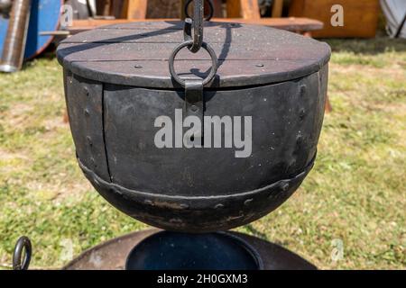 A large black metal cooking pot replica used by medieval vikings displayed by a re-enactment troupe at a village fair Stock Photo