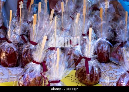 Red toffee apples on sticks wrapped in clear cellophane for sale at a market stall at a country fair Stock Photo