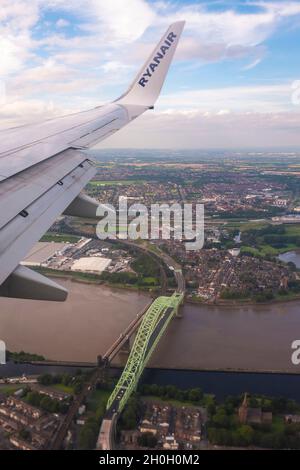 A Ryanair airplane flies above the Silver Jubilee Bridge over river Mersey on August 06, 2020 in Liverpool, United Kingdom Stock Photo