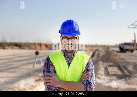 Portrait of satisfied and confident engineer with helmet and vest on building site Stock Photo