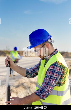 Construction worker holding laser measuring tool on building site Stock Photo