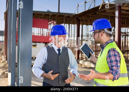 Senior and young engineers talking angrily about project at building site Stock Photo
