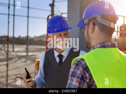 Senior and young engineers talking angrily about project at building site Stock Photo