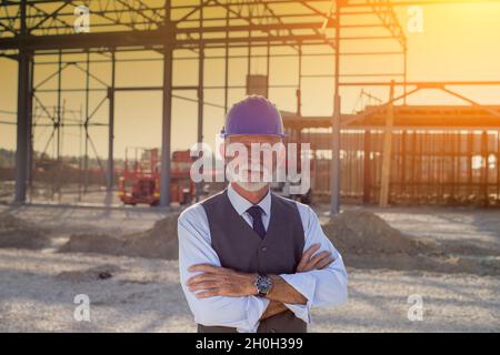 Portrait of foreman with helmet and vest in front of metal structure on building site Stock Photo