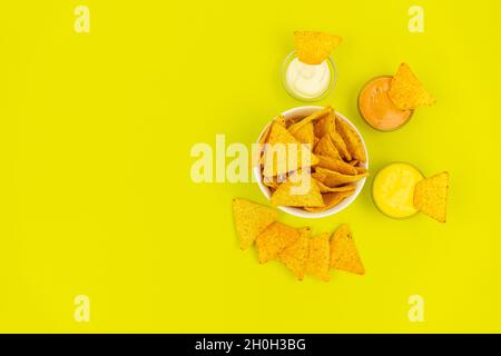 Mexican food. Tortilla chips in a white plate on a colored background with dipping sauce. Stock Photo
