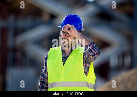 Portrait of cheerful engineer with helmet and vest on building site Stock Photo