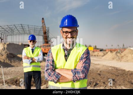 Portrait of satisfied and confident engineer with helmet and vest on building site Stock Photo
