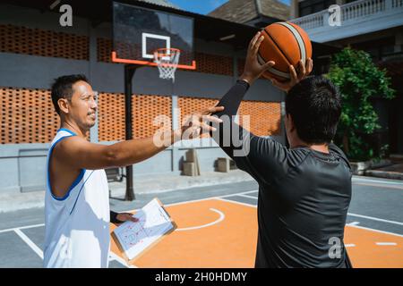 a coach advises a male basketball player to shoot the ball in the hoop