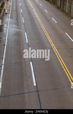 Wet roadway of four lane road seen from overhead, stone walls on both sides, vertical aspect Stock Photo