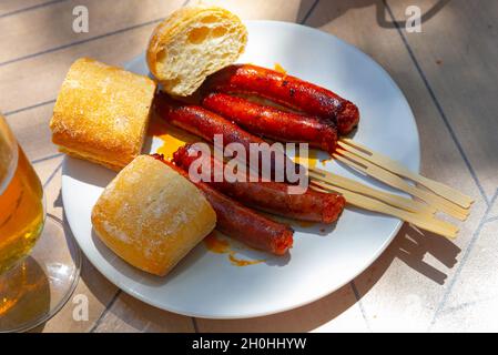 Mildly spiced grilled mini sausages chistorra. Tapa from Basque Country cuisine Stock Photo