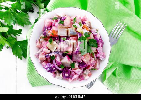 Finnish Rosoli salad with herring, beetroot, potatoes, pickled or pickled cucumbers, carrots, onions and eggs, seasoned with mayonnaise in a bowl agai Stock Photo