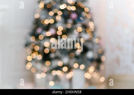 Festive garland lights on christmas tree in white interior blurred background. Stock Photo