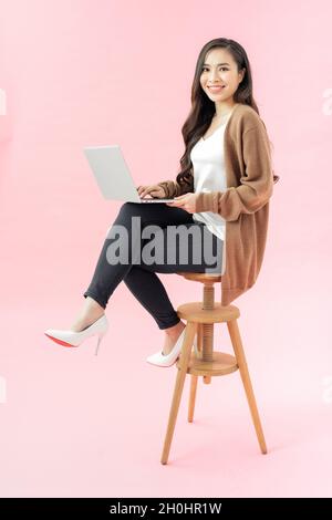 Smilling young woman using laptop pc computer isolated on the blue background Stock Photo