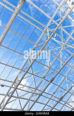 Abstract contemporary architectural vertical photo. Internal structure of roof with metal frame and glass under blue sky on a daytime