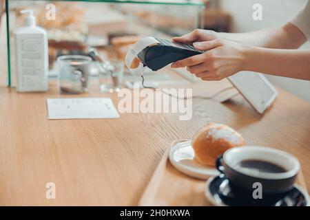 Female barista using terminal for contactless payment in cafeteria Stock Photo