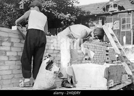 Two women bricklayers raising a wall in the USA. (undated photo) [automated translation] Stock Photo