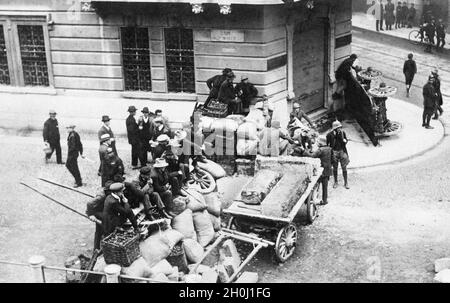 'Men have erected a barricade of carts, sacks and baskets in Via San Marco in Milan, on the corner of Via Castelfidardo, and are now sitting on top. They control the passage, two of them wearing steel helmets and carrying rifles. The photo was taken in 1922 after the ''March on Rome'' at the end of October and the resulting takeover of the government by the Fascists. [automated translation]' Stock Photo