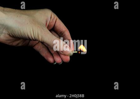 Hand holding burning match stick on black background Stock Photo