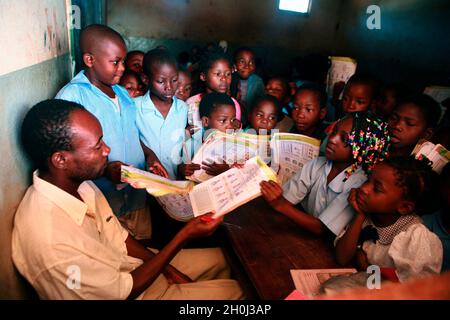 Children at Montes Namuli Primary School in Gurue crowd around their teacher to have their work marked. Gurue, Zambezia Province, Mozambique. March 10, 2010.. Stock Photo