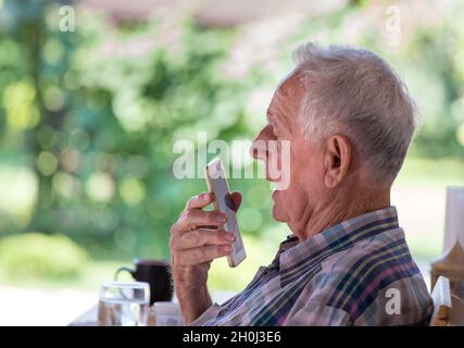 Senior man sitting in park and talking on cell phone Stock Photo