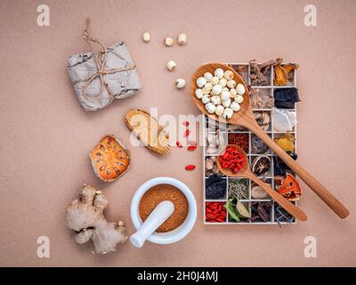 Alternative health care dried various Chinese herbs in wooden box , dried quince ,ginger and lotus seed in wooden spoon with mortar on brown backgroun Stock Photo