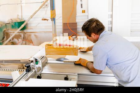 A man cutting wooden piece with a ring saw on the table to use in the local furniture production Stock Photo