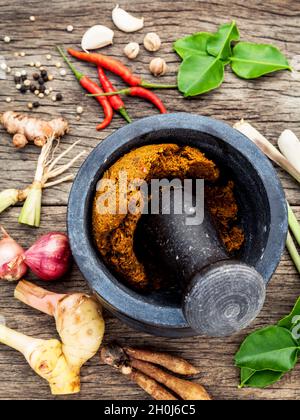 Assortment of Thai food Cooking ingredients and Paste of thai popular food red curry  with mortar and pestle on rustic wooden background. Spices ingre Stock Photo