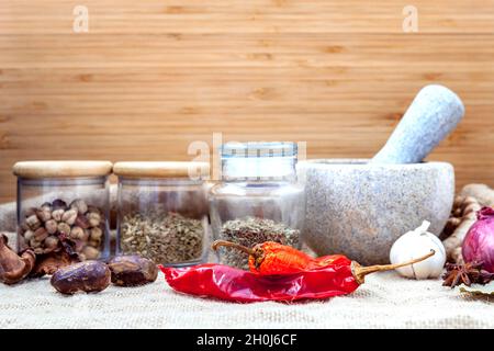 Assortment of spices ingredients of thai popular food red curry with mortar set up on wooden table. Stock Photo