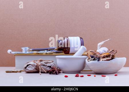 Alternative health care dried various Chinese herbs in the white mortar and herbs capsule on brown  background. Stock Photo