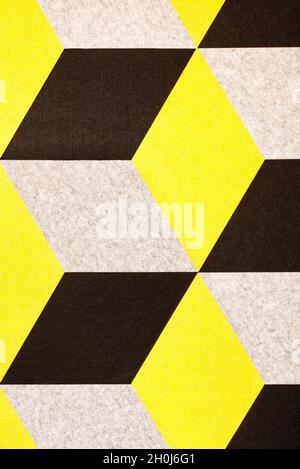 Abstract ornament of geometric woolen yellow, beige and brown rhombuses in the interior of the wall. Stock Photo