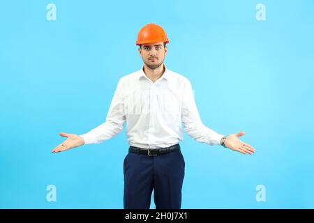 Businessman builder in misunderstanding on blue background. Stock Photo