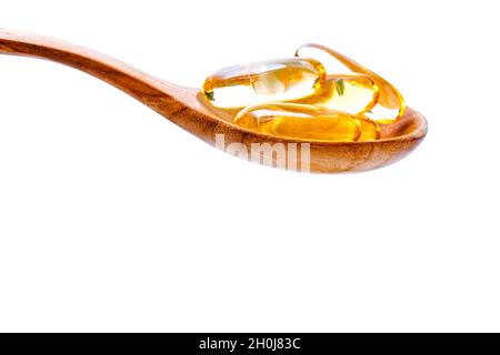 Spoonful of gel capsules of omega 3. Close up capsules fish oil in wooden spoon .The supplement high vitamin E, omega 3 and DHA . Capsules fish oil wi Stock Photo